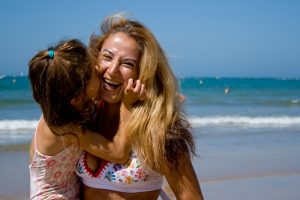 madre e hija en la playa riendo