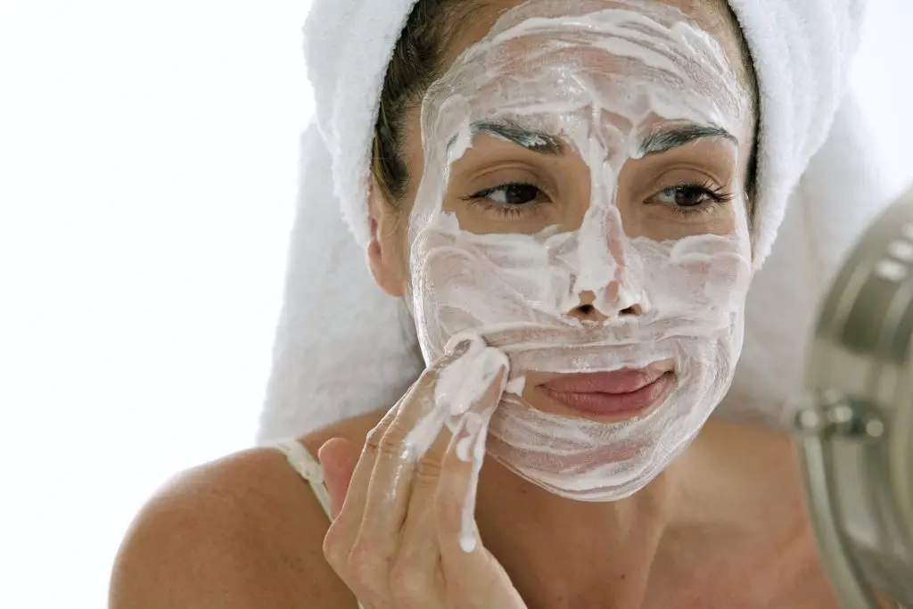 Close-up of a young adult woman applying cleanser to her face