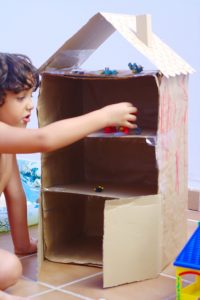 niño jugando con una casa de carton
