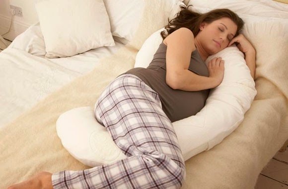 Mujer durmiedno sobre una almohada para embarazada