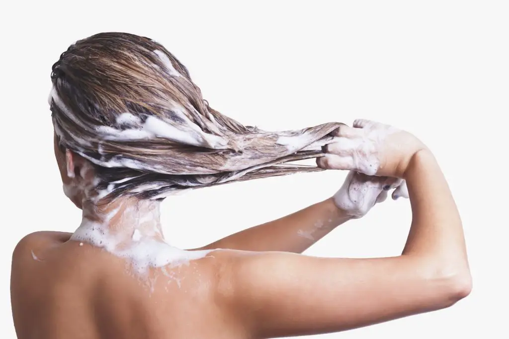 mujer lavando su cabello con shampoo