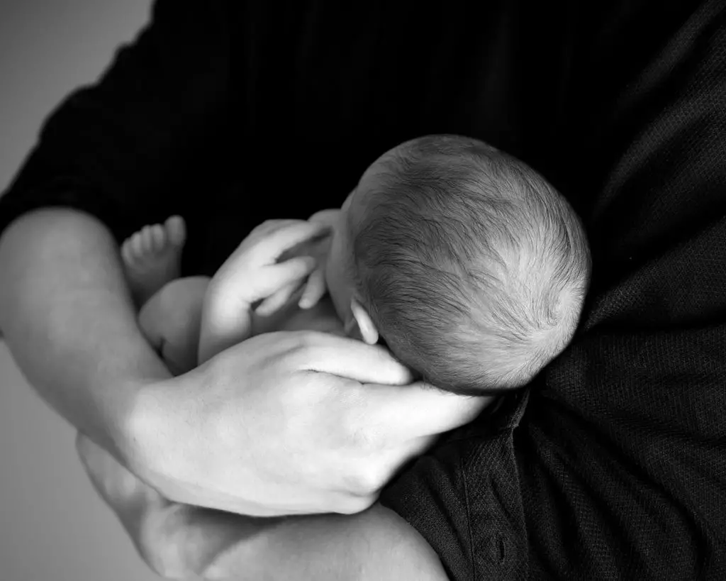hipotonía muscular papa sosteniendo a un bebe en sus brazos