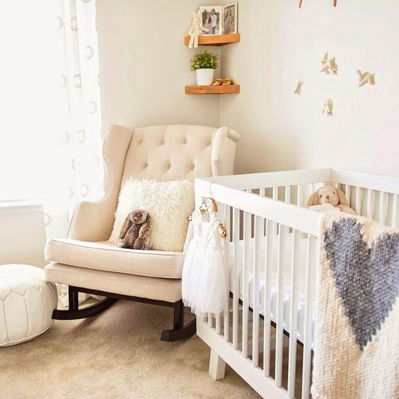 Silla mecedora color beige junto a una cuna de bebé Silla mecedora color beige junto a una cuna de bebé