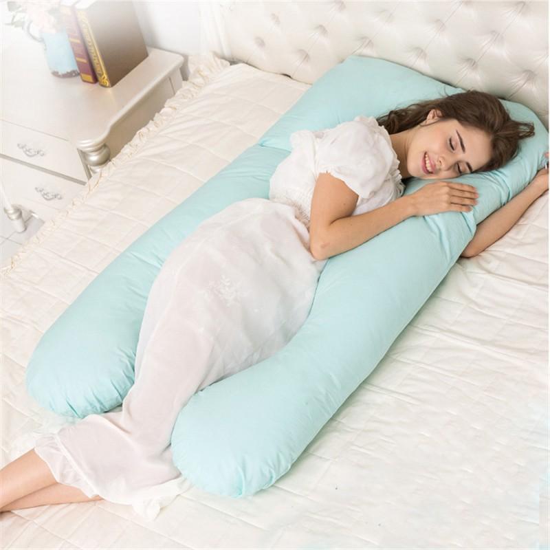 Mujer embarazada acostada sobre una cama con una almohada para embarazadas