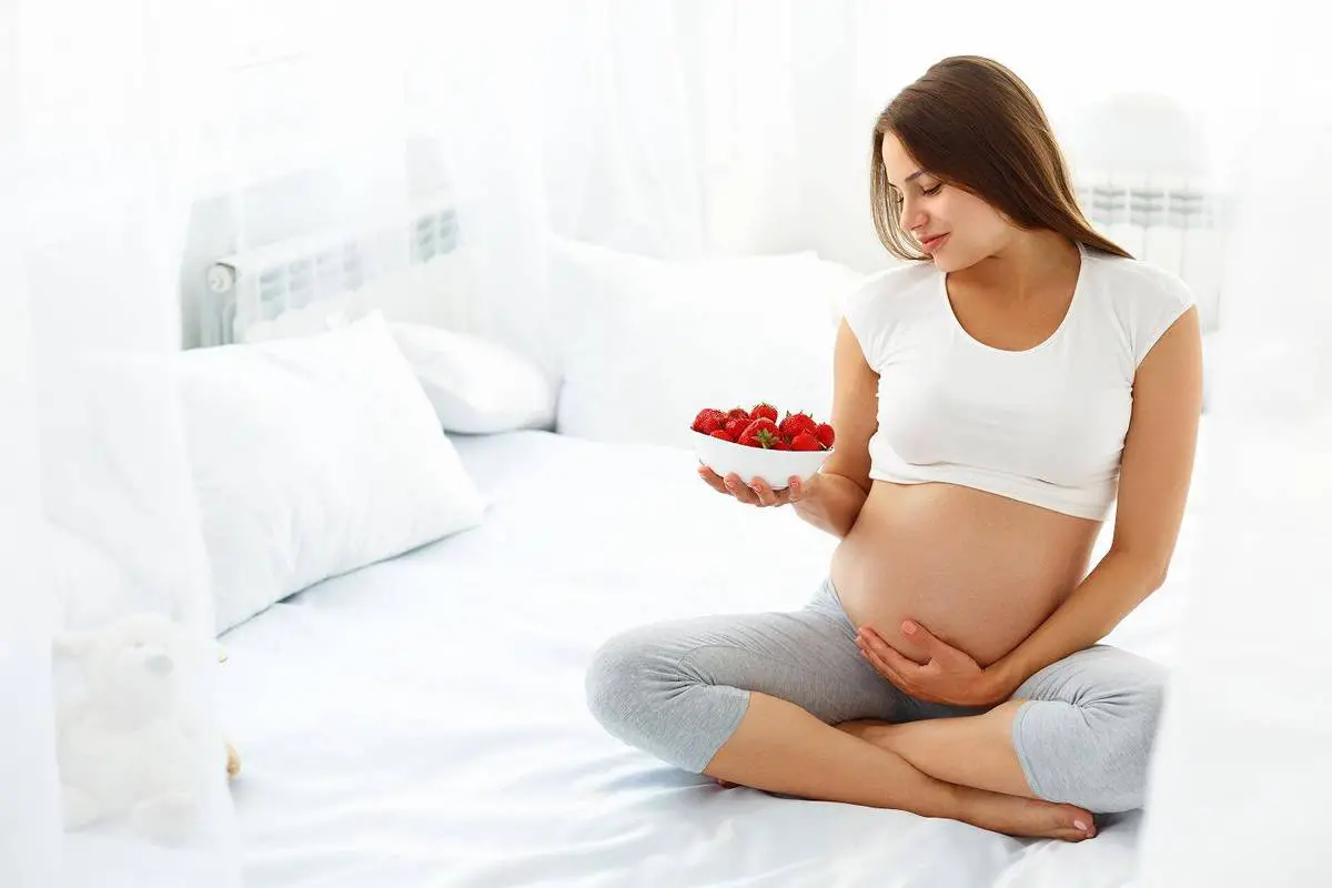 mujer embarazada con un plato de frutas