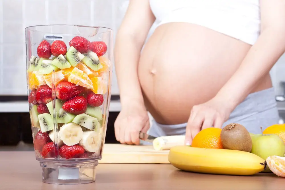mujer embarazada preparando ensalada de frutas