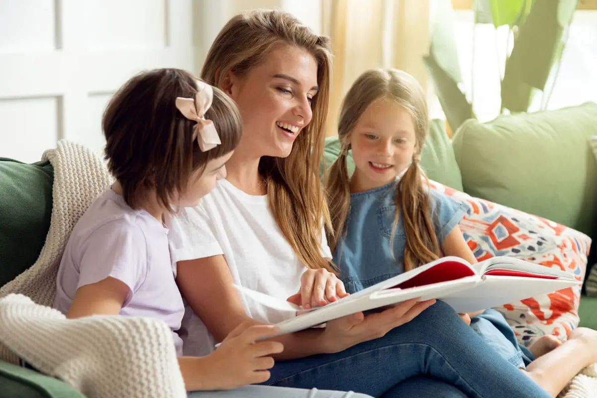 mamá leyendole un libro a sus hijas